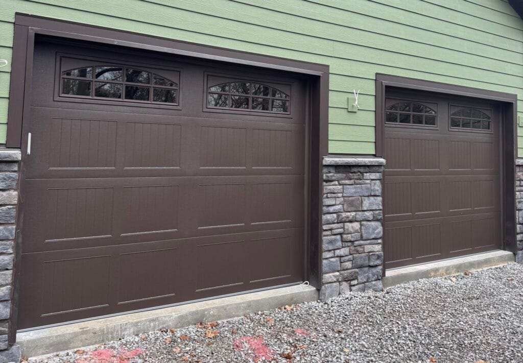Brown garage doors with window inserts on a new home with stone accents